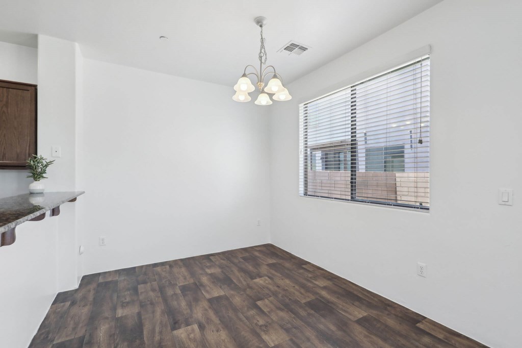 A room with wooden flooring and a window with blinds.
