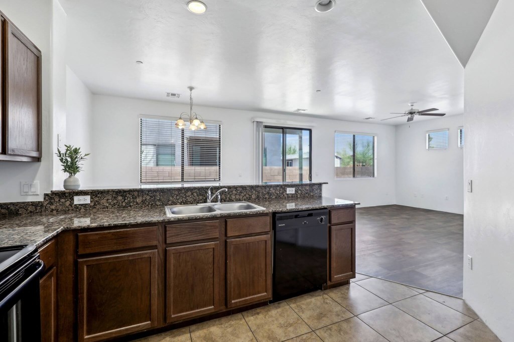 A kitchen with brown cabinets and a black dishwasher.
