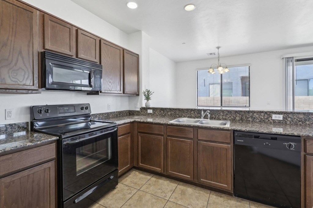 A kitchen with brown cabinets and black appliances.