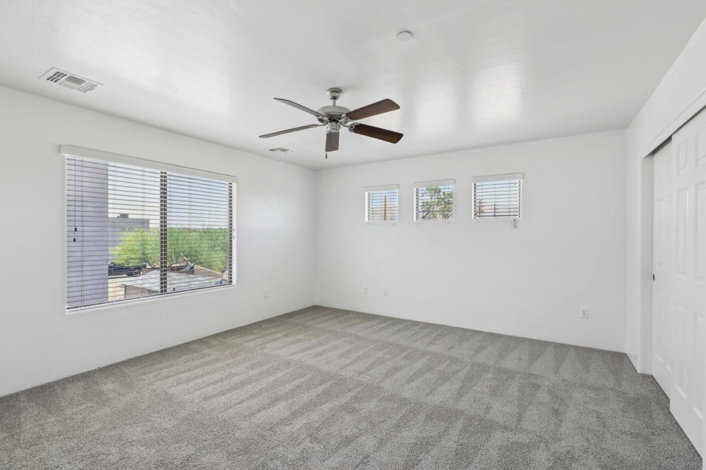 Bedroom with a ceiling fan and carpeted floor.