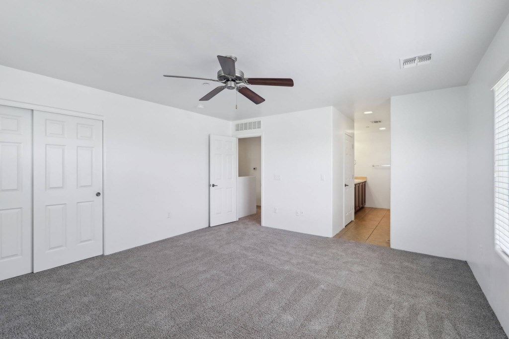 A room with a ceiling fan and carpeted floor.