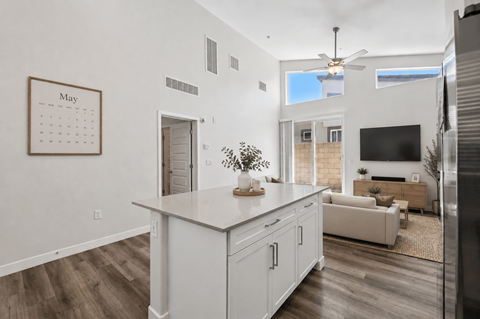 A kitchen with a calendar on the wall and a refrigerator on the right.
