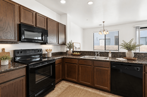 A kitchen with dark wood cabinets and black appliances.