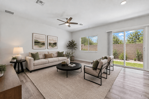 A living room with a white couch, a coffee table, and a ceiling fan.