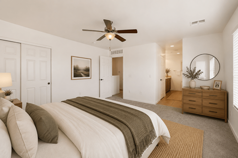 A bedroom with a large bed and a ceiling fan.