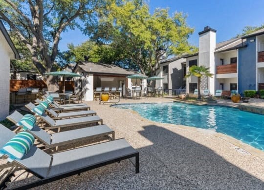 a swimming pool with lounge chairs in front of a building at Heatherstone, Dallas