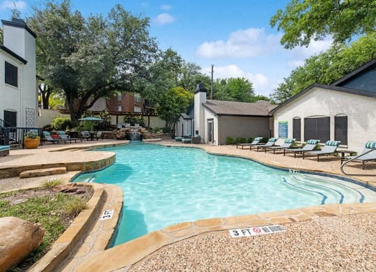 a large swimming pool with lounge chairs in front of a house at Heatherstone, Dallas, 75287