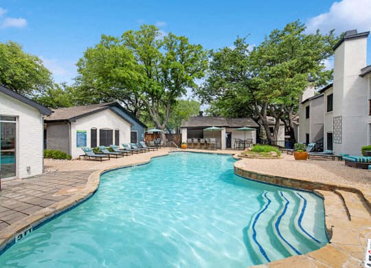 a large swimming pool with buildings and trees in the background a large swimming pool with buildings and trees in the background at Heatherstone, Texas
