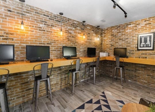 a brick walled room with a long bar with three televisions at Heatherstone, Dallas, TX