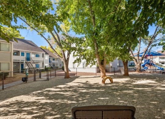 a park with benches and trees in front of houses