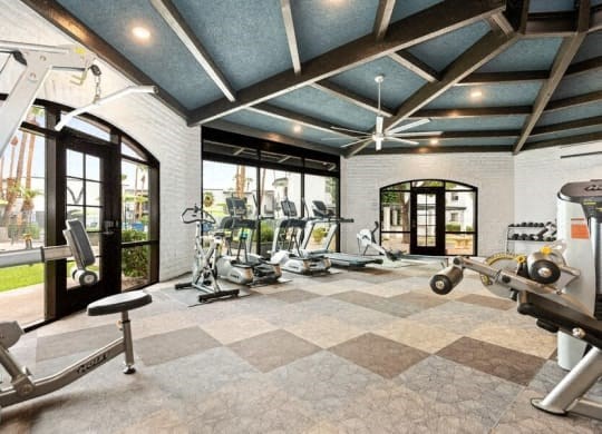 the home gym has plenty of exercise equipment and windows