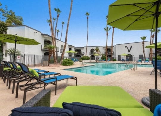 a swimming pool with lounge chairs and umbrellas