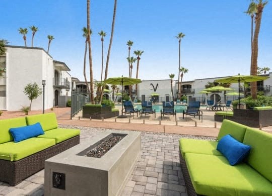 a patio with green couches and chairs and tables and palm trees