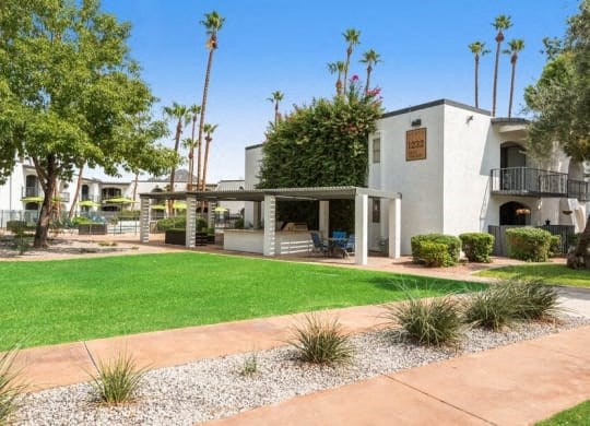 the front yard of a building with a green lawn and palm trees