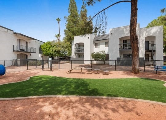 the backyard of an apartment building with a playground and grass