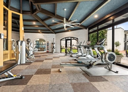 the gym has plenty of exercise equipment and a large window
