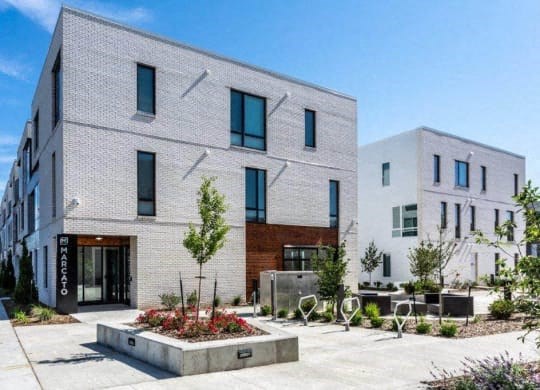 a white brick building with a courtyard in front of it at Marcato, Kansas City, 64108
