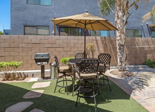 a patio with a table and chairs under an umbrella