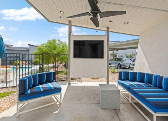 a patio with blue chairs and a tv on a wall