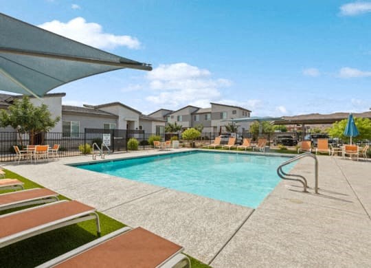 a swimming pool with lounge chairs and buildings in the background