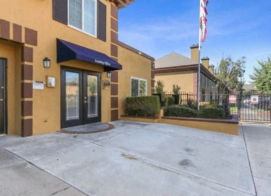 a yellow building with an flag and a driveway