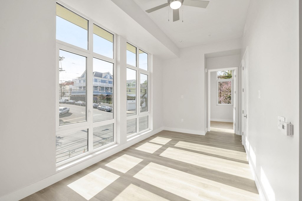 a living room with large windows and a ceiling fan