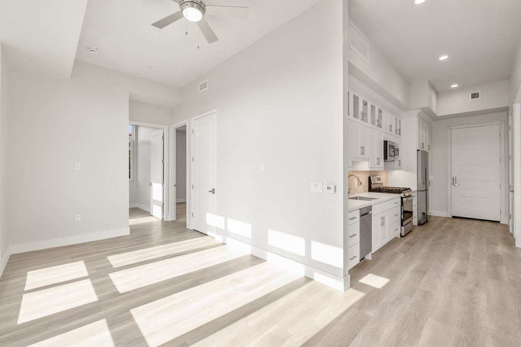 a living room with a kitchen and a ceiling fan