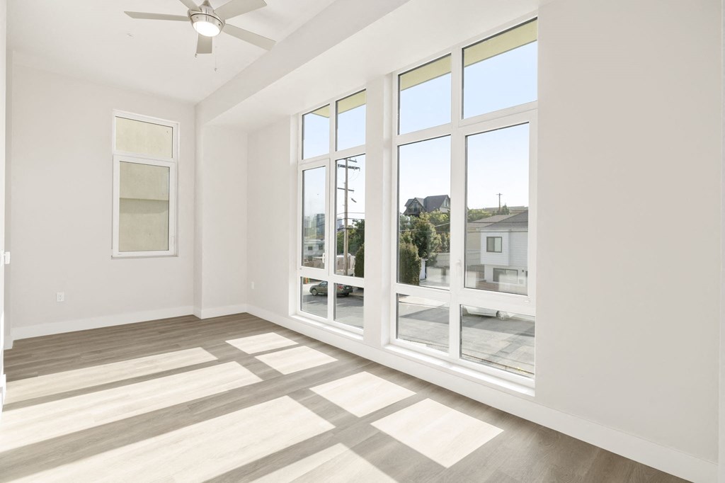 a living room with large windows and a ceiling fan