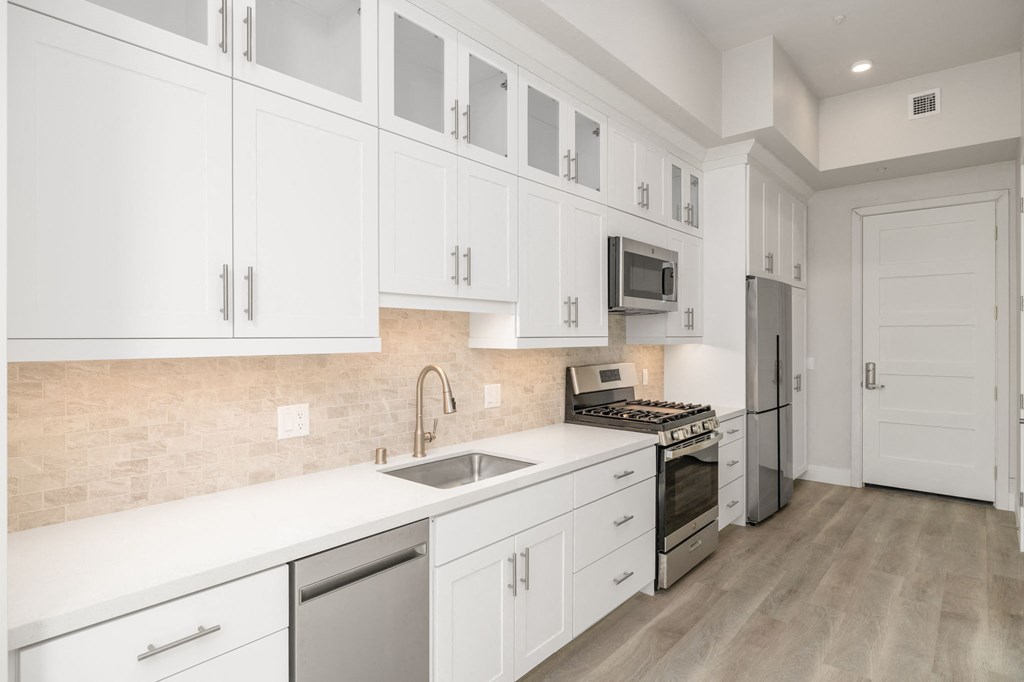 a white kitchen with stainless steel appliances and white cabinets