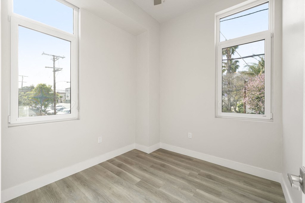an empty room with a wooden floor and two windows