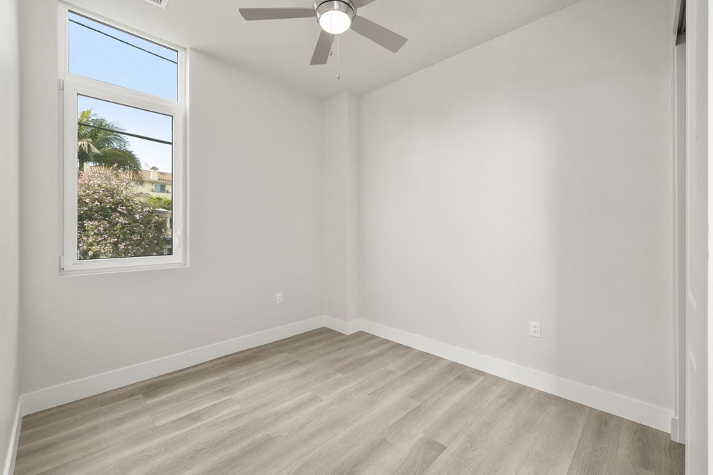 an empty room with white walls and a ceiling fan