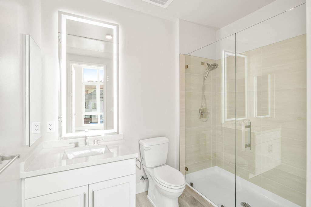 a white bathroom with a toilet and a shower