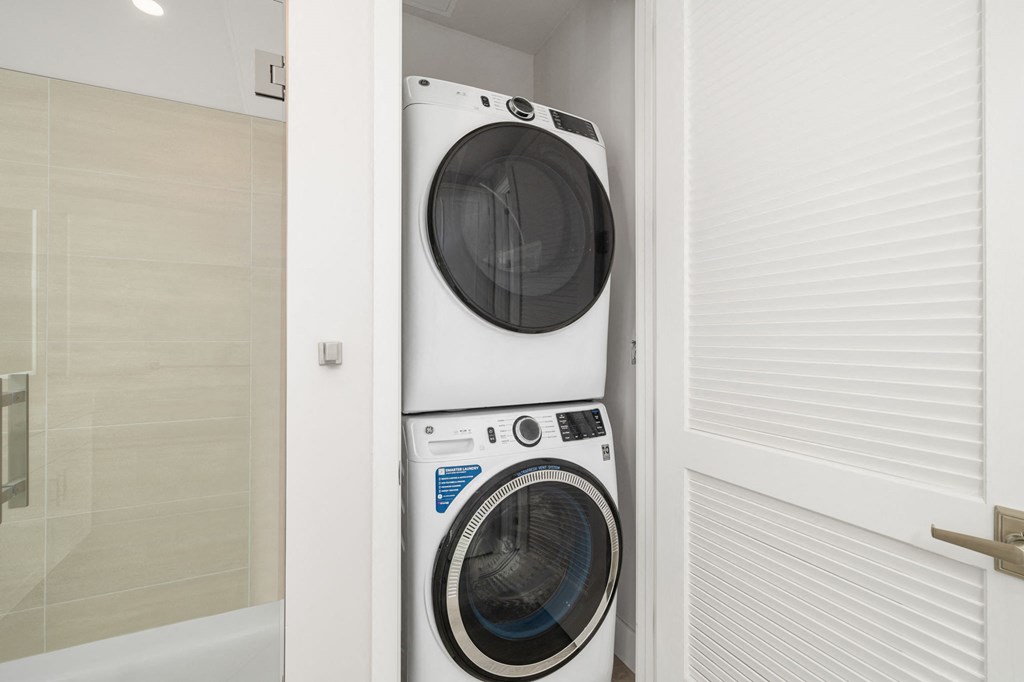 a washing machine in a bathroom with a pattern of arms on the wall