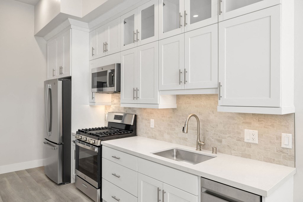 a white kitchen with stainless steel appliances and white cabinets