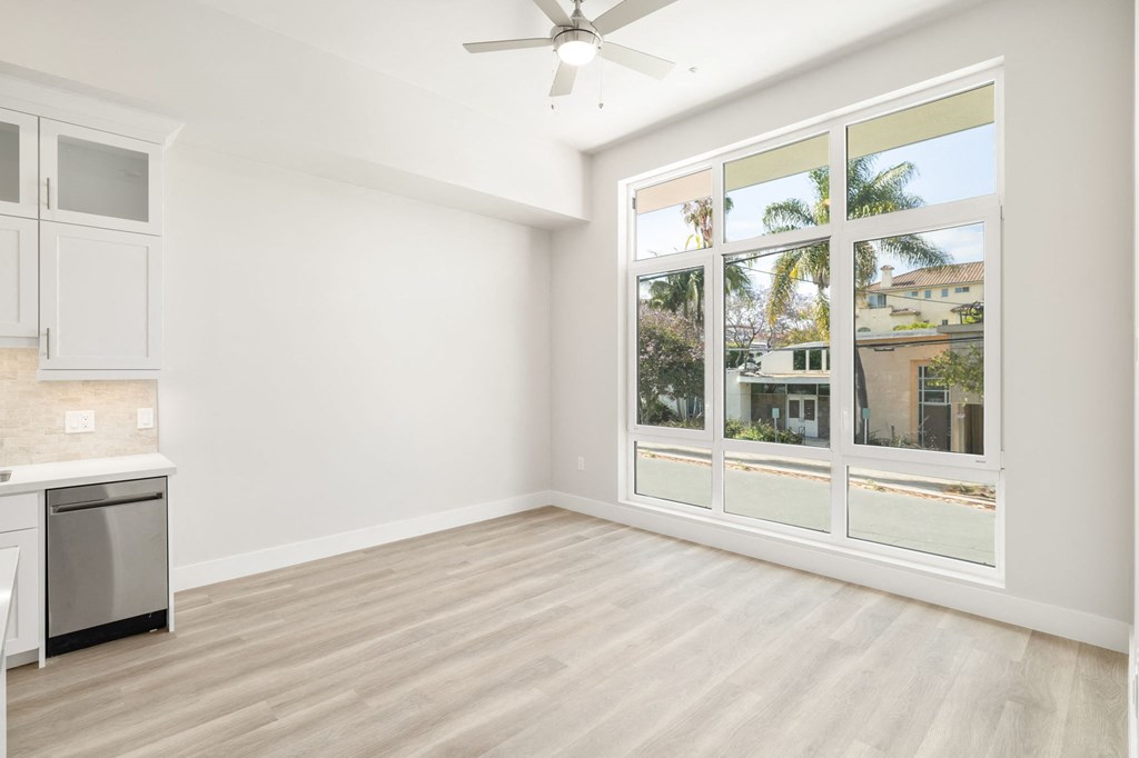an empty living room with a large window and a kitchen
