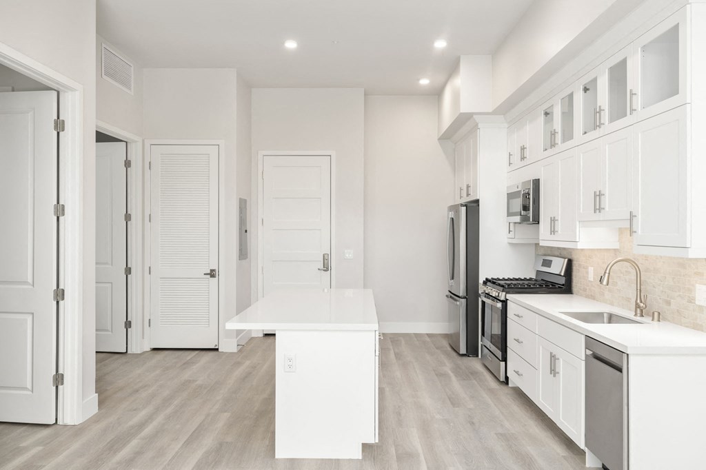 a long hallway with white cabinets and white walls and floors and a white counter top