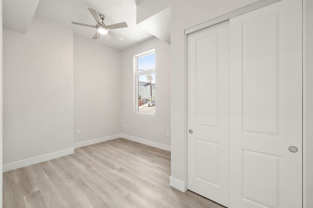 an empty bedroom with white walls and a ceiling fan