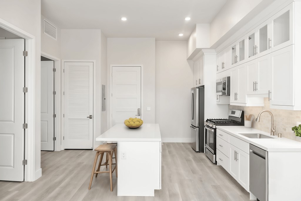 a white kitchen with a white counter top and a stainless steel