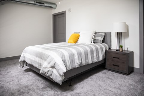 A bedroom with a bed, nightstand, and lamp.