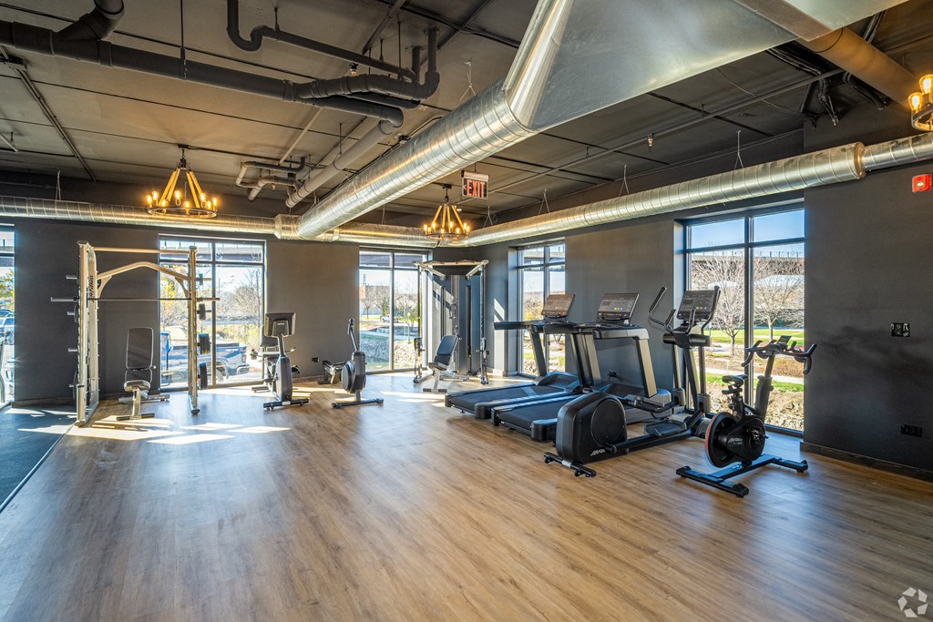 a gym with fitness equipment and windows in a building with wood floors