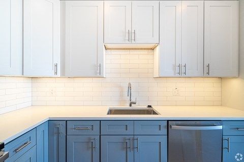 A kitchen with white cabinets and blue drawers.
