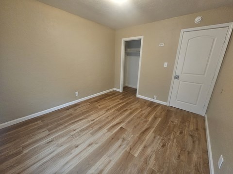 A room with wooden flooring and a white door.