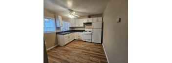 A kitchen with white appliances and wooden floors.