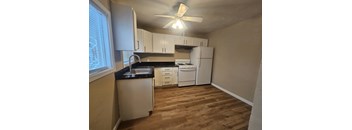 A kitchen with white cabinets and a black countertop.