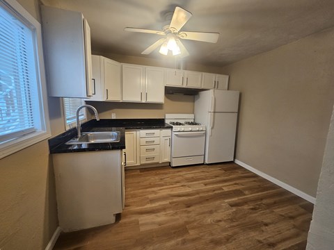 A kitchen with white cabinets and a black countertop.