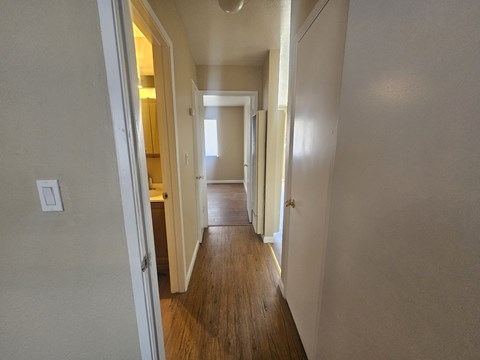 A long hallway with doors on both sides and a light switch on the wall.