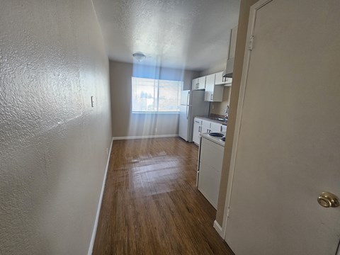 A kitchen area with white cabinets and a wooden floor.
