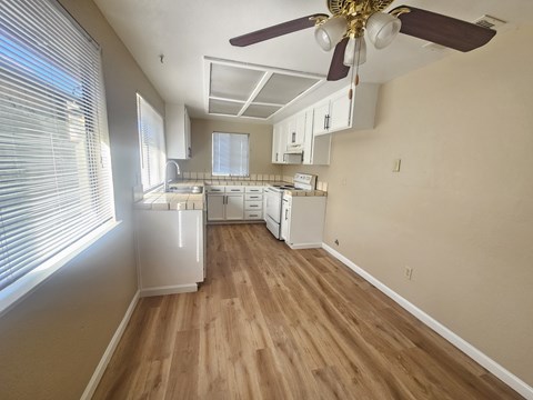 A kitchen with a ceiling fan and wooden floors.