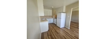 A kitchen with white appliances and wooden floors.