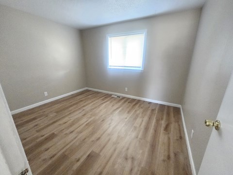 A room with wooden flooring and a window.